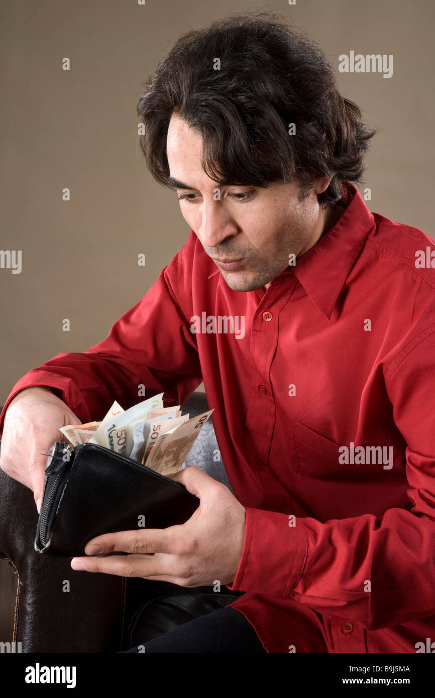 Giovane uomo che guarda il suo portafoglio completo, lieto Foto Stock