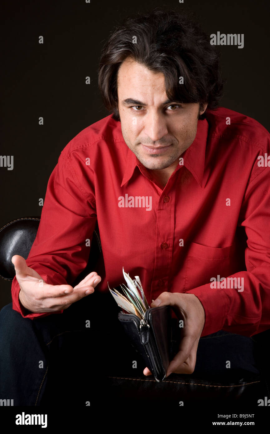 Giovane uomo felicemente cercando nel suo portafoglio completo Foto Stock