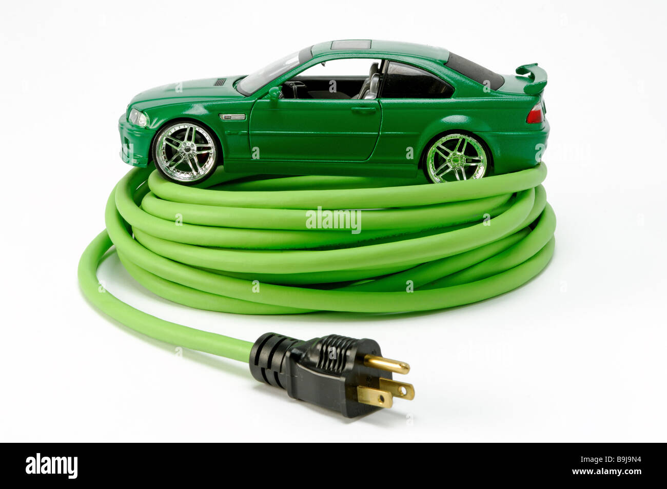 Un verde automobile automobile su un verde avvolto a spirale prolunga elettrica cavo di alimentazione con una spina Foto Stock
