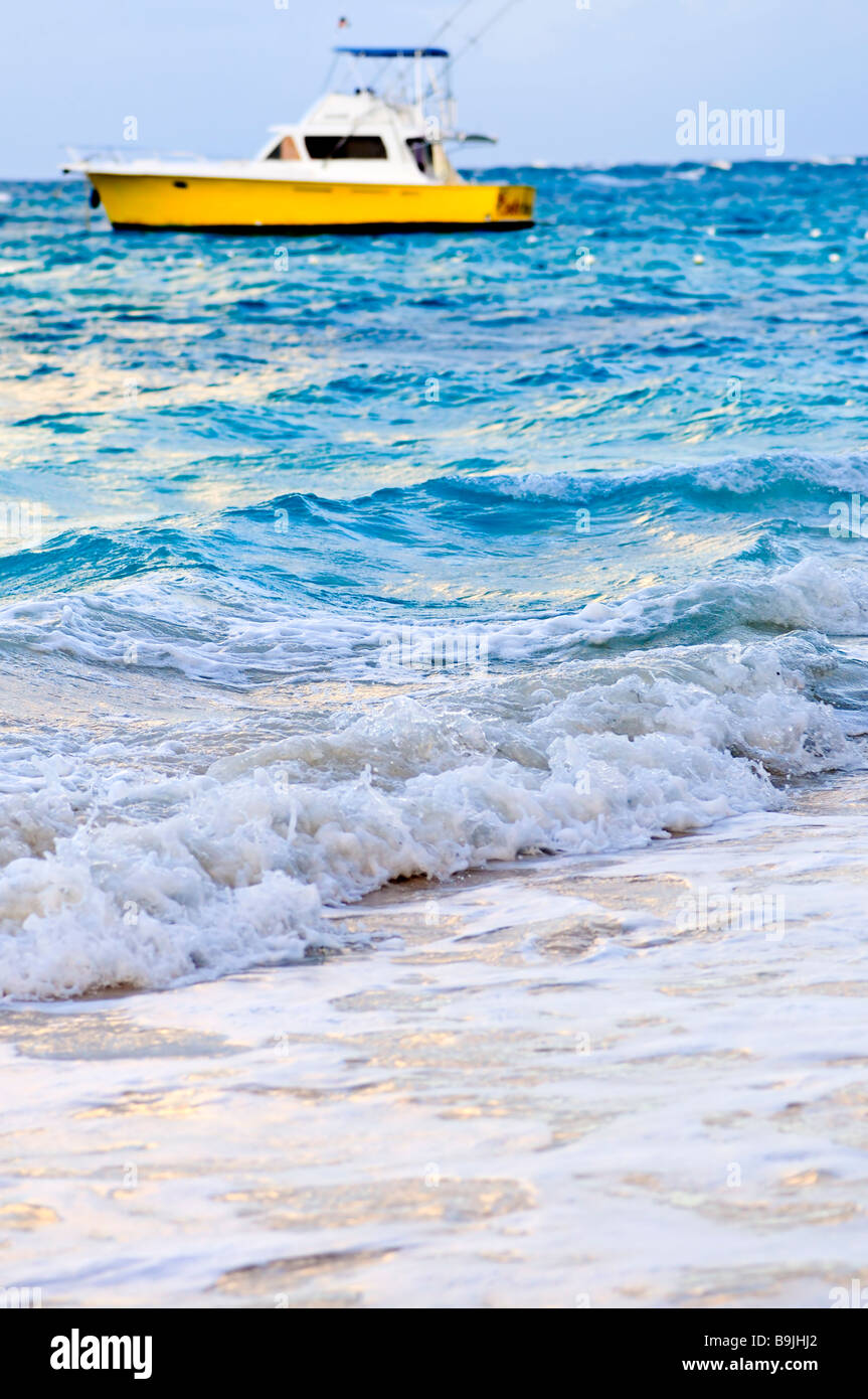 Onde che si infrangono sulla spiaggia tropicale con barca a distanza Foto Stock