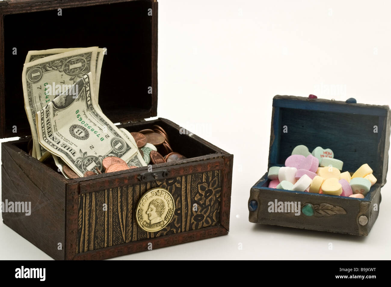 Due piccoli scrigni di un tesoro, uno riempito con i soldi e un altro con heart-shaped candy Foto Stock