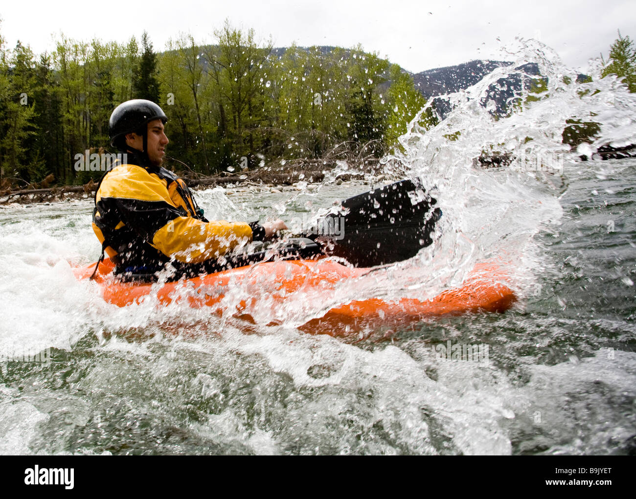 Un playboater gode di una piccola onda sulle rive di un fiume. Foto Stock