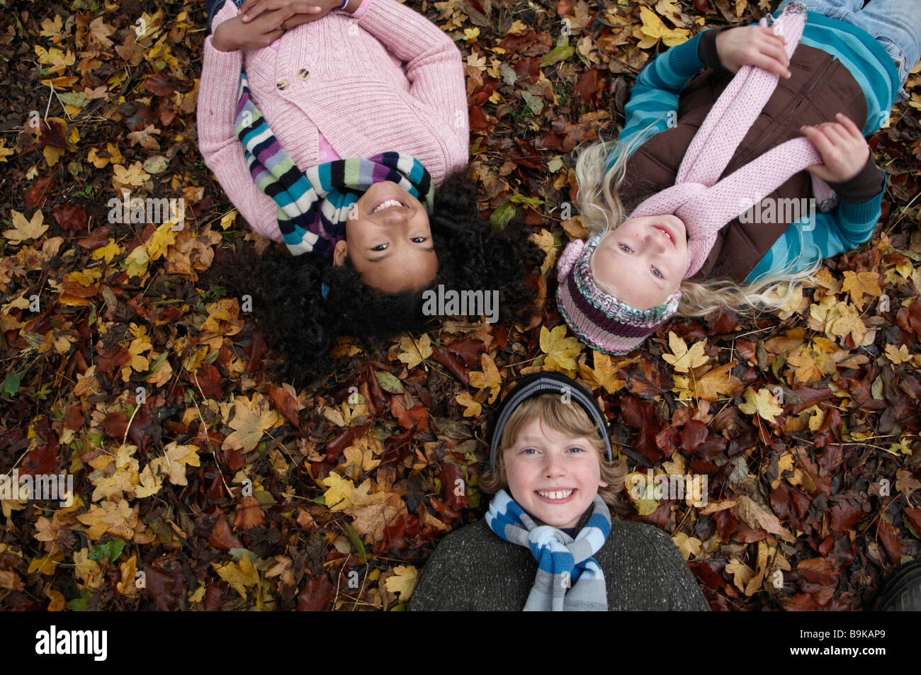 Tre amici giacente su foglie di autunno Foto Stock
