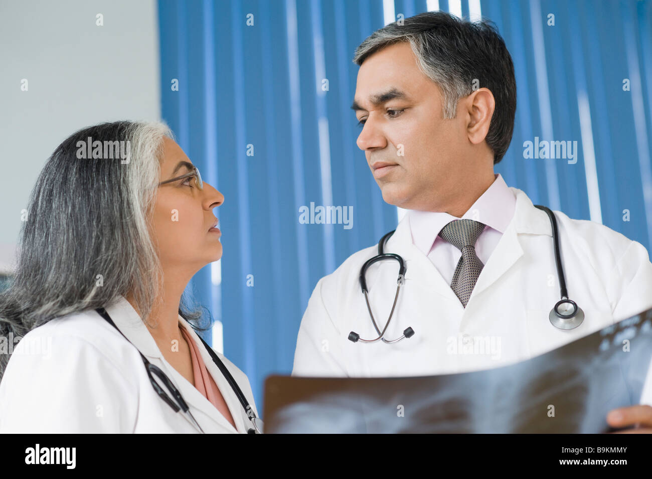 Medico donna discutere con un medico in possesso di un x-ray relazione Foto Stock