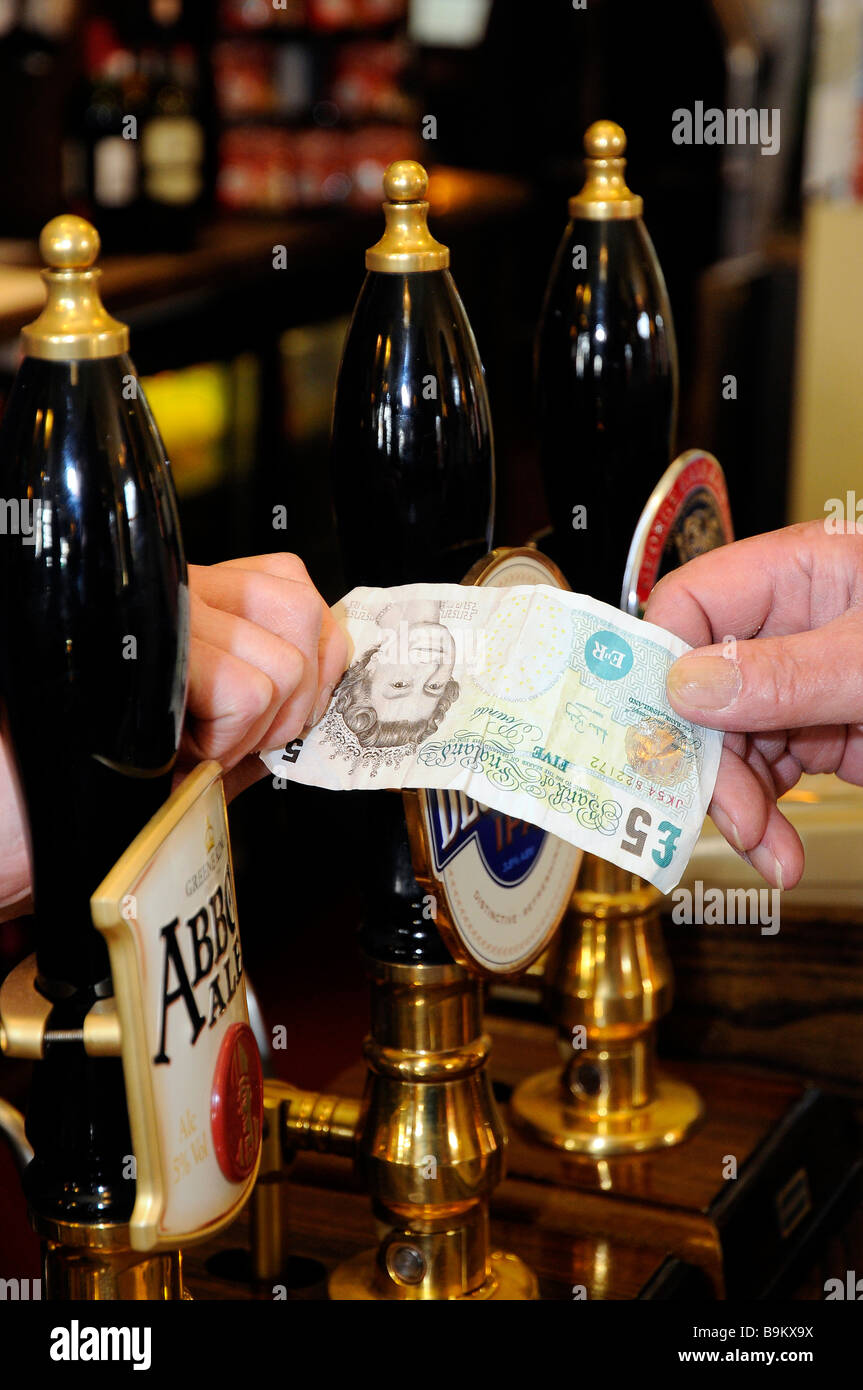 Un Inglese di cinque pound nota utilizzata per pagare in un tradizionale pub inglese, con real ale handpumps. Foto Stock