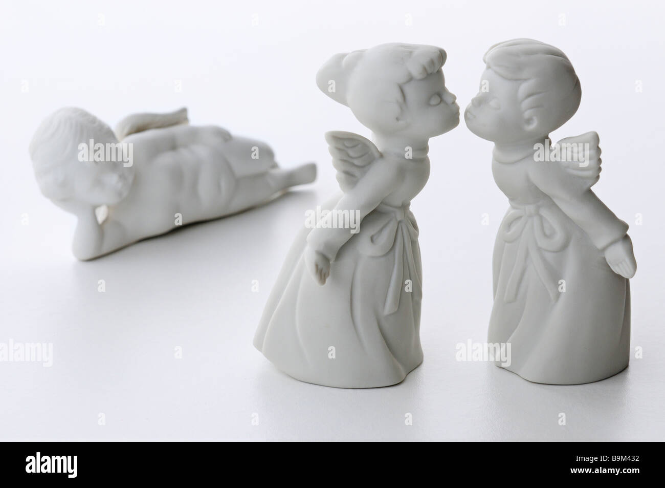 Porcellana Bianca un ragazzo e una ragazza baciare gli angeli con un terzo angelo cherubino sdraiato guardando in uno sfondo bianco Foto Stock