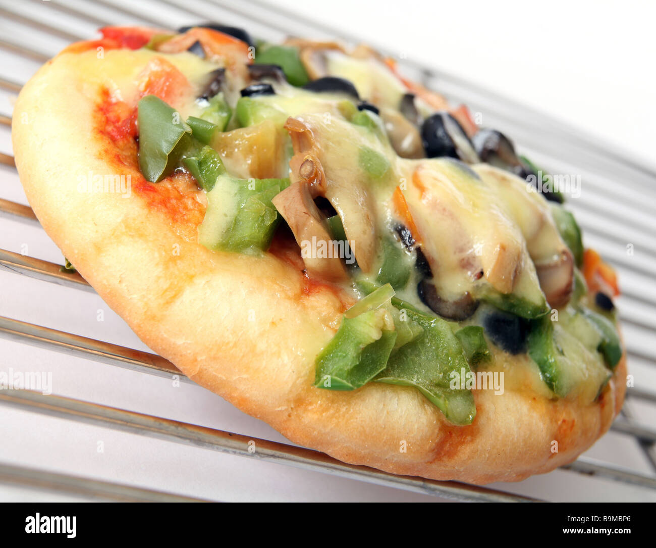 Piccola pizza conditi con formaggio, peperoni Funghi,e pomodoro su di un raffreddamento per rack Foto Stock