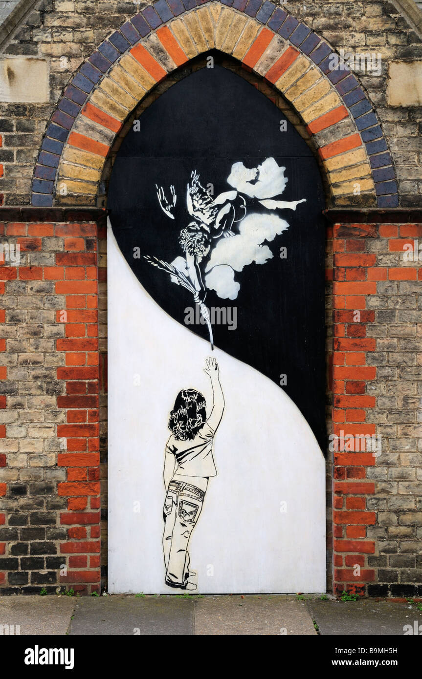 Arte di strada di un bambino e di angelo sulla porta della Santa Chiesa Philips, Mill Road Cambridge Inghilterra REGNO UNITO Foto Stock