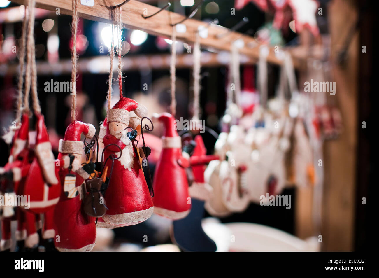 Babbo Natale artigianale o Babbo Natale al mercatino di Natale. Ornamenti festivi appesi a uno stallo, profondità di campo bassa con luci bokeh. Foto Stock