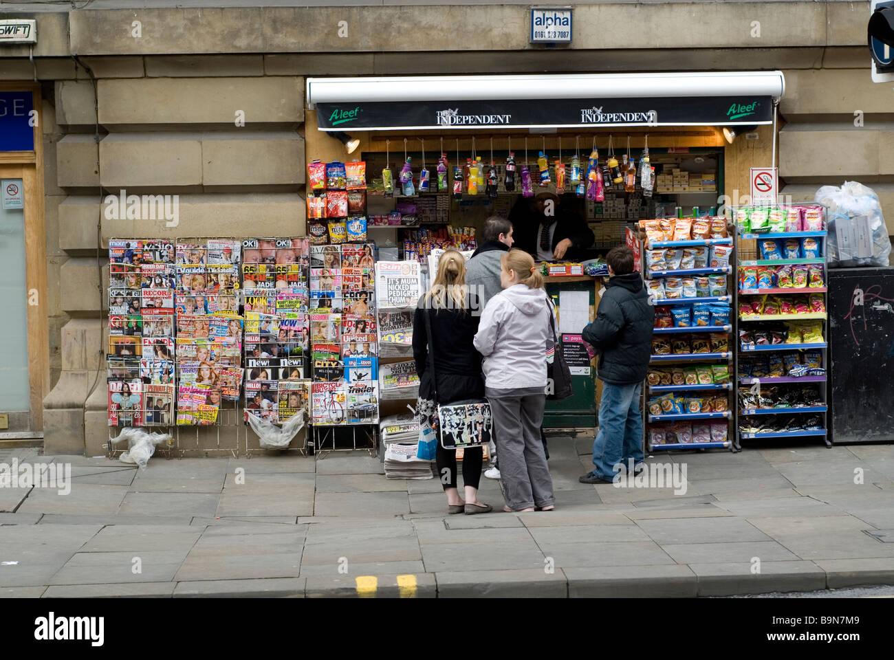 Le persone al di fuori di una piccola edicola in Manchester City Centre Regno Unito Foto Stock