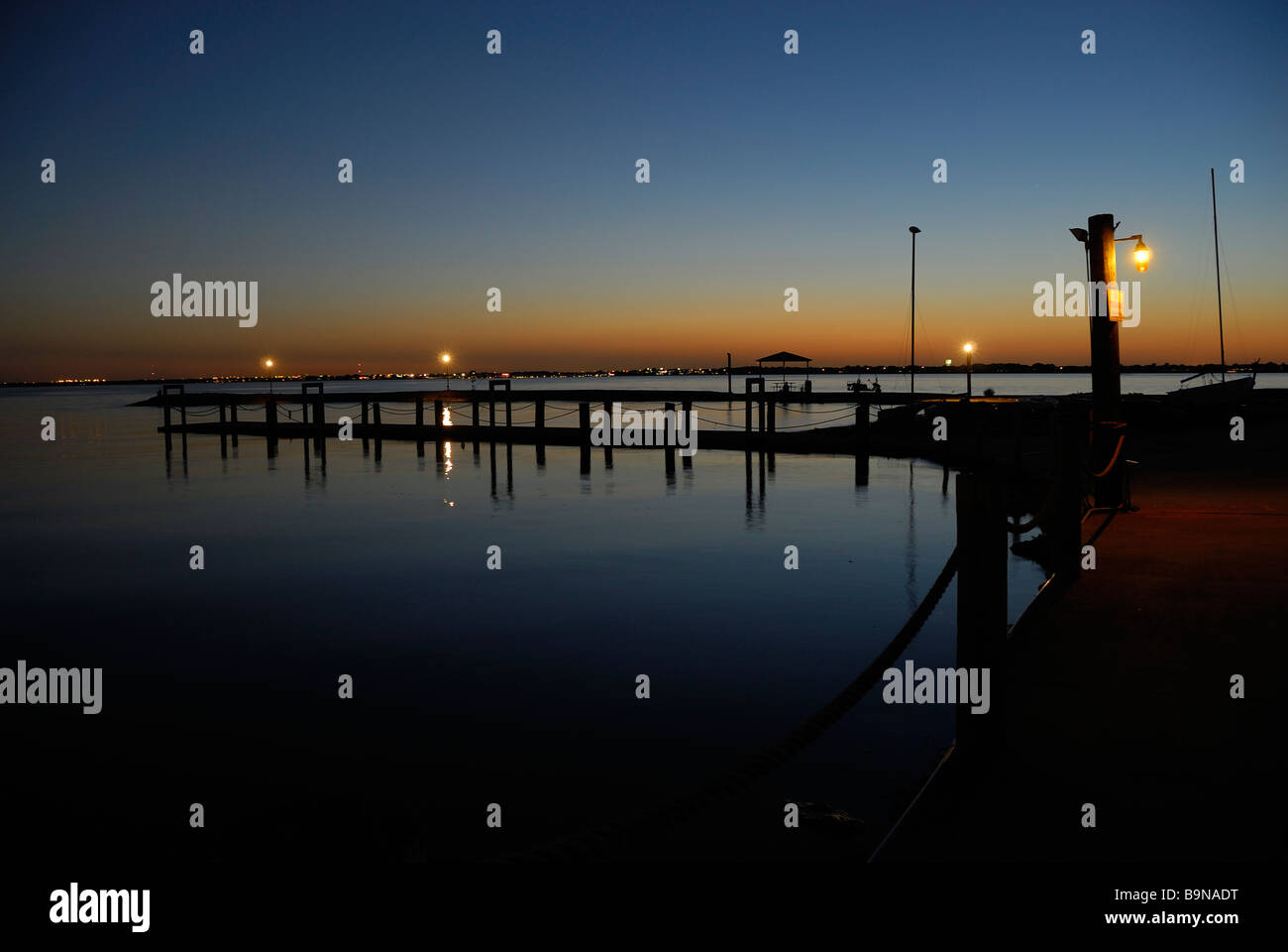 La luce del giorno dando modo al cielo notturno in un molo di pesca sul lago Foto Stock