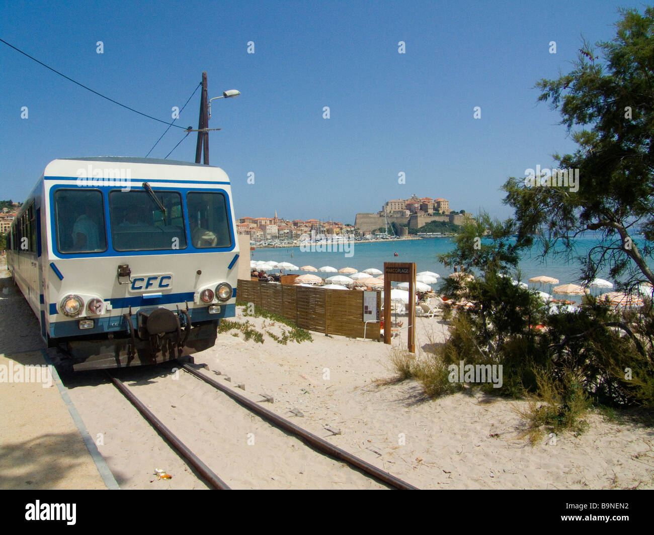 La parte anteriore di mare della linea ferroviaria con la cittadella di Calvi in background. Calvi, Corsica, Francia. Foto Stock