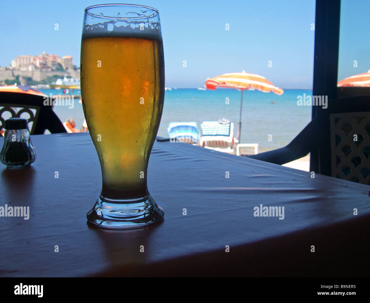 Di fronte al mare, con una birra e sun umberellas Calvi, Corsica, Francia. Foto Stock