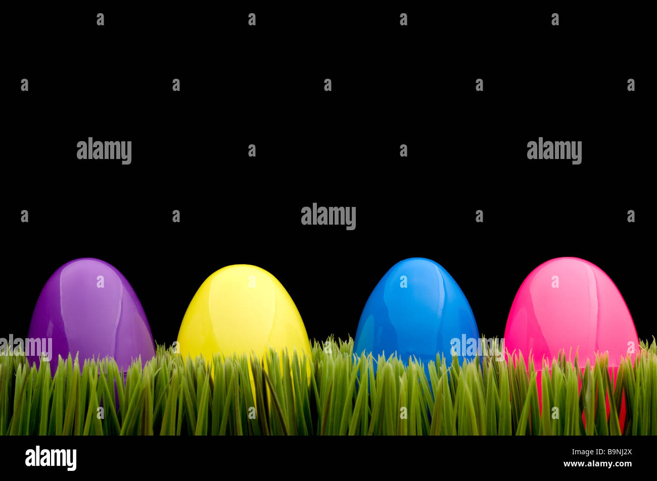Uova colorate su erba con uno sfondo nero Foto Stock