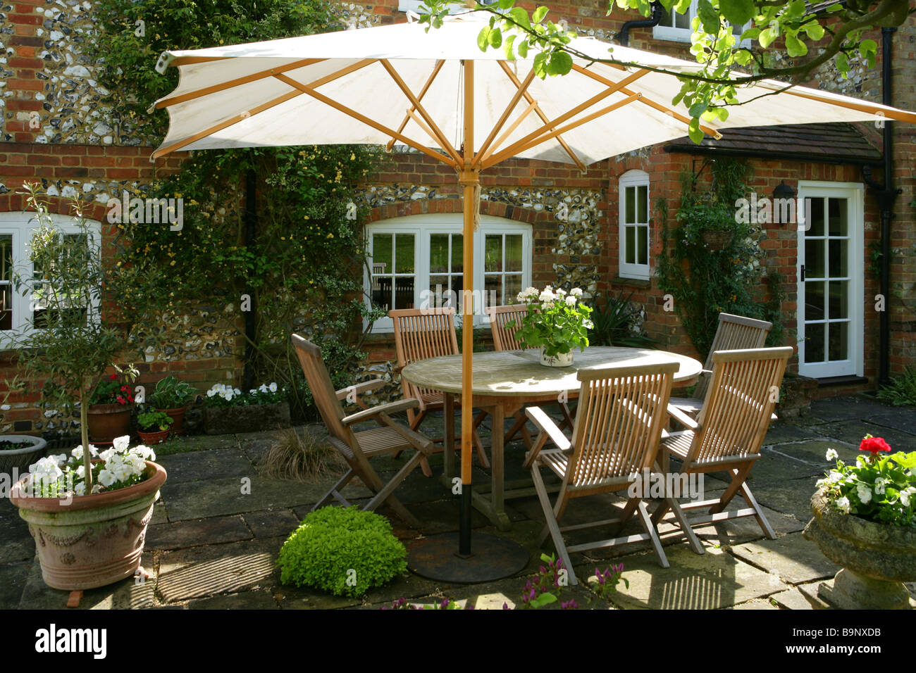 Un domestico country estate scena. La fotografia mostra un patio di una casa di campagna inglese con un esterno set da pranzo. Foto Stock