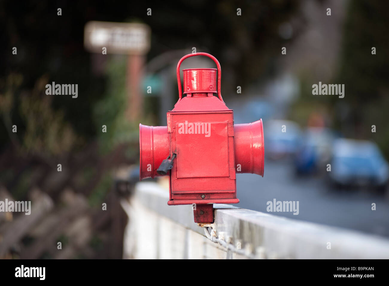 Stazione della Guardia dipinte di rosso olio lampada montato su di un incrocio ferroviario barriera Foto Stock