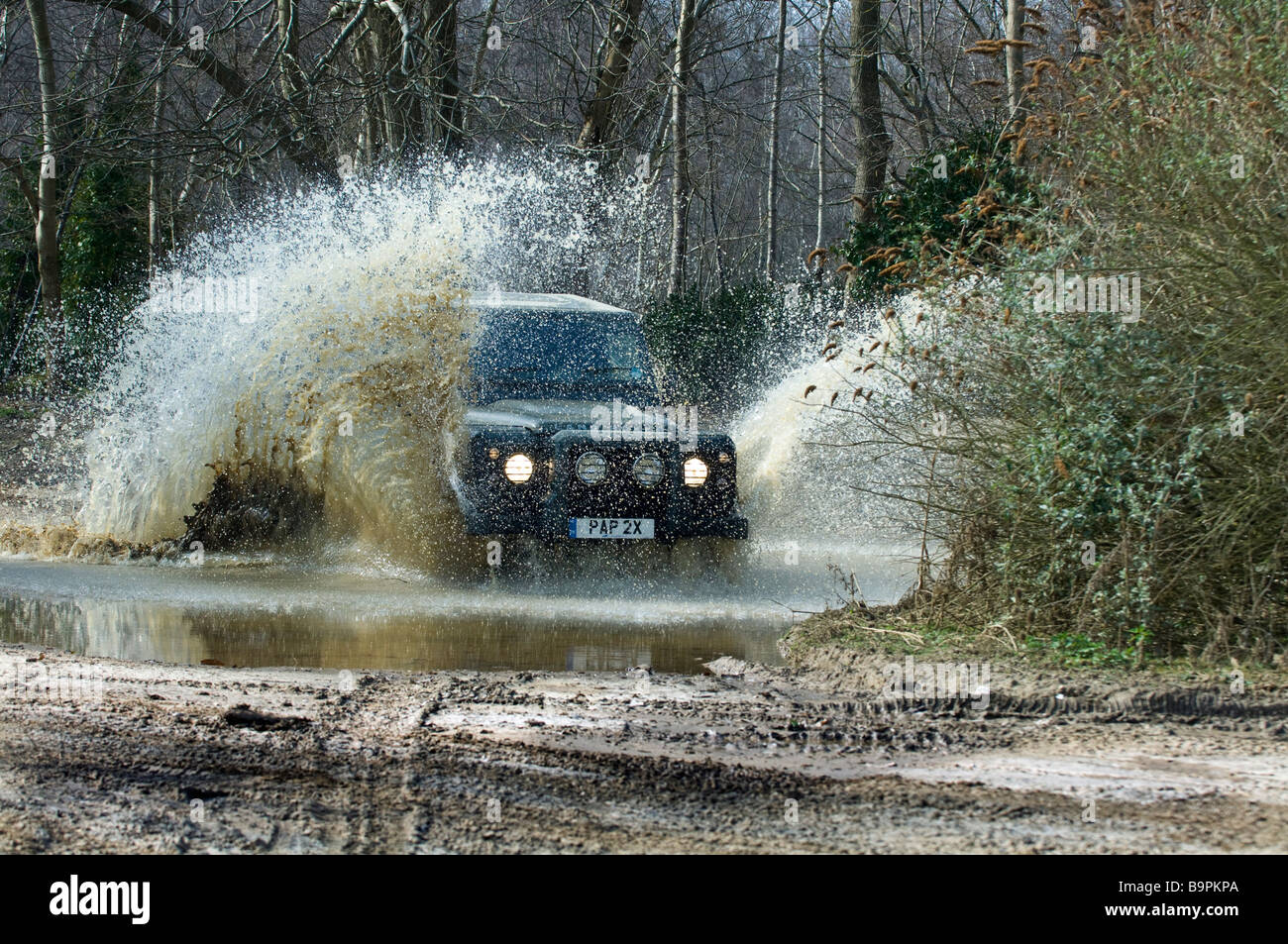 Il Land Rover Defender 90 velocità attraverso una strada allagata in Slindon West Sussex Regno Unito durante un esercizio di circolazione su strada Foto Stock