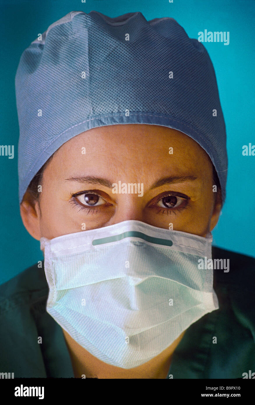 Femmina con il chirurgo in questione espressione, indossando maschera chirurgica e scrub. Foto Stock