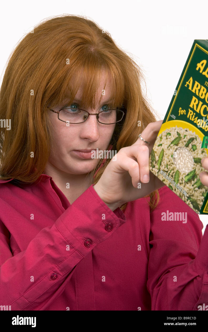 Una donna leggendo attentamente le informazioni di prodotto su una confezione per alimenti Foto Stock