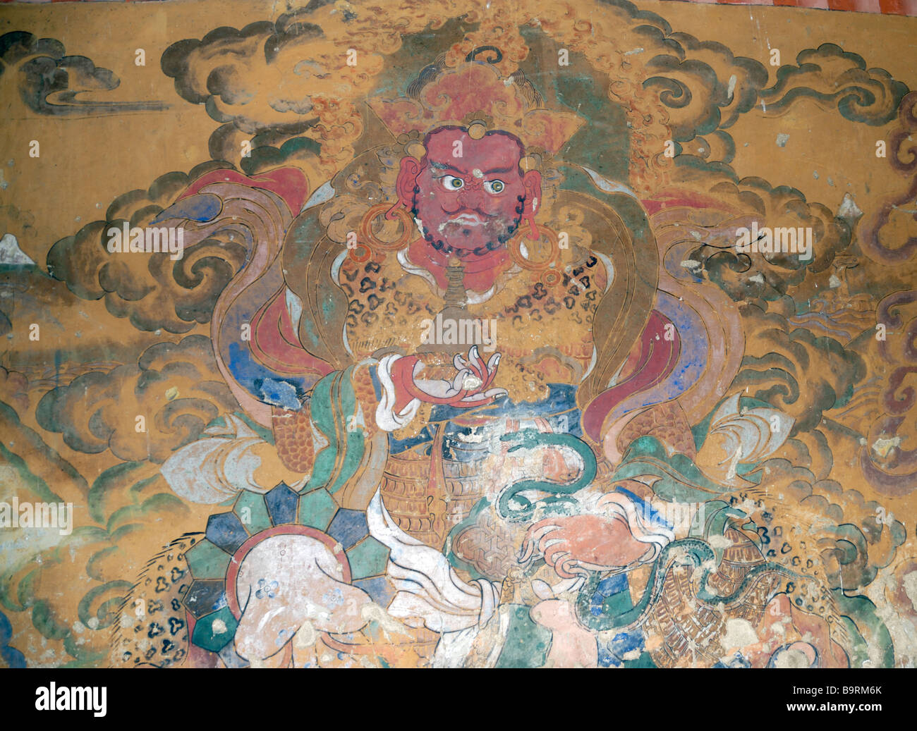Antico dipinto murale di un essere con una pelle di leopardo mantello, orecchini, un serpente e un Kadampa o Nirvana stupa in mano. Foto Stock