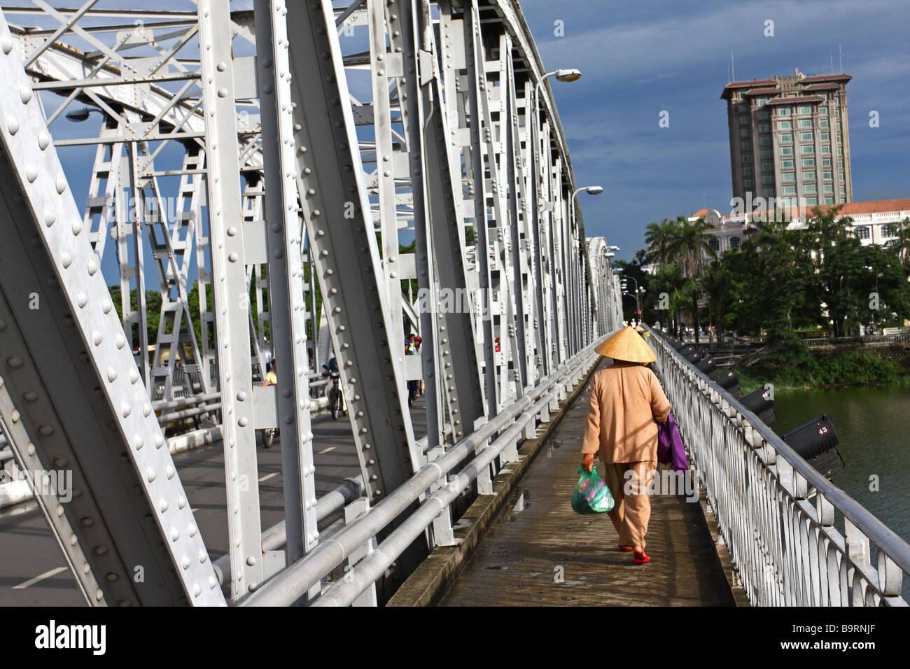 Scena di strada. Donna vietnamita con il tradizionale cappello conico camminando sul ponte in tinta. Il Vietnam Foto Stock