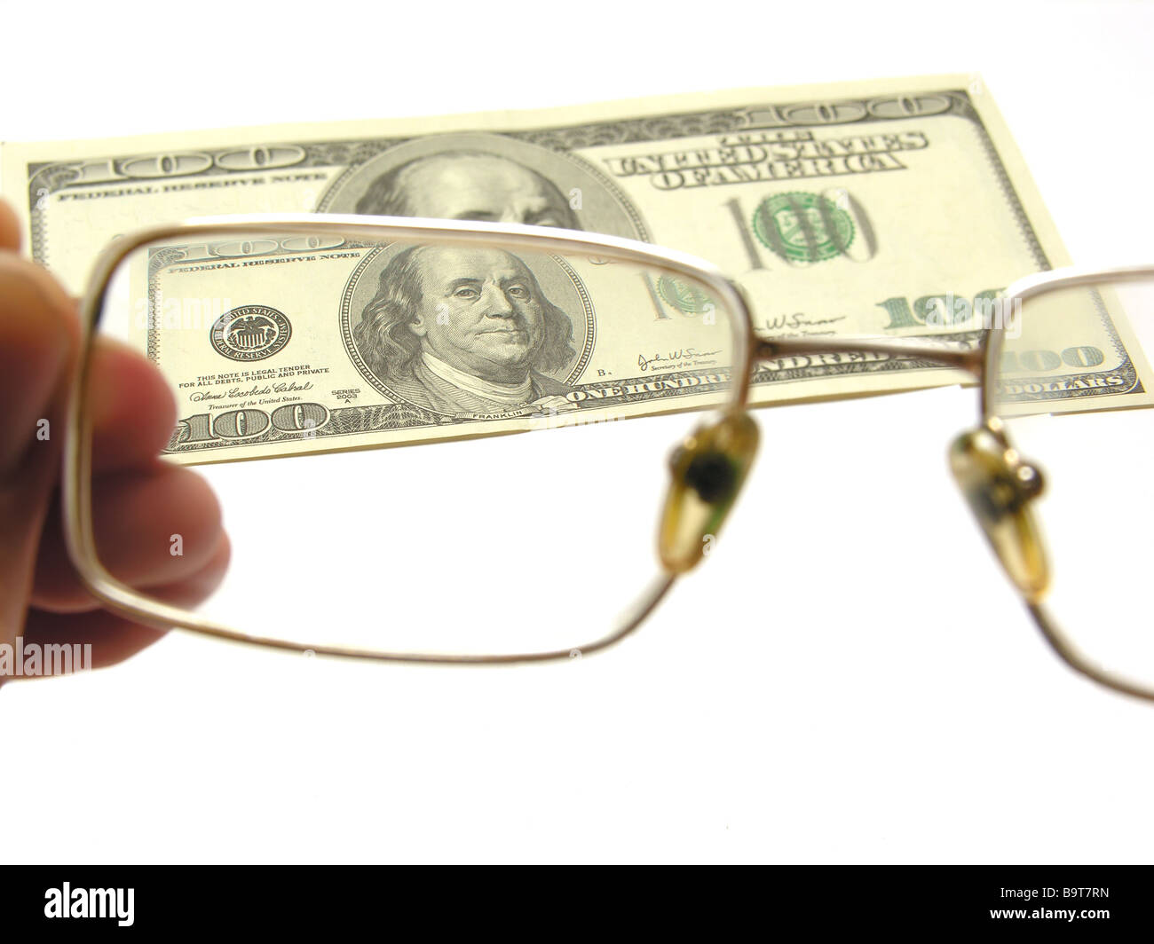 Un centinaio di dollari dal primo piano attraverso gli occhiali su sfondo bianco Foto Stock