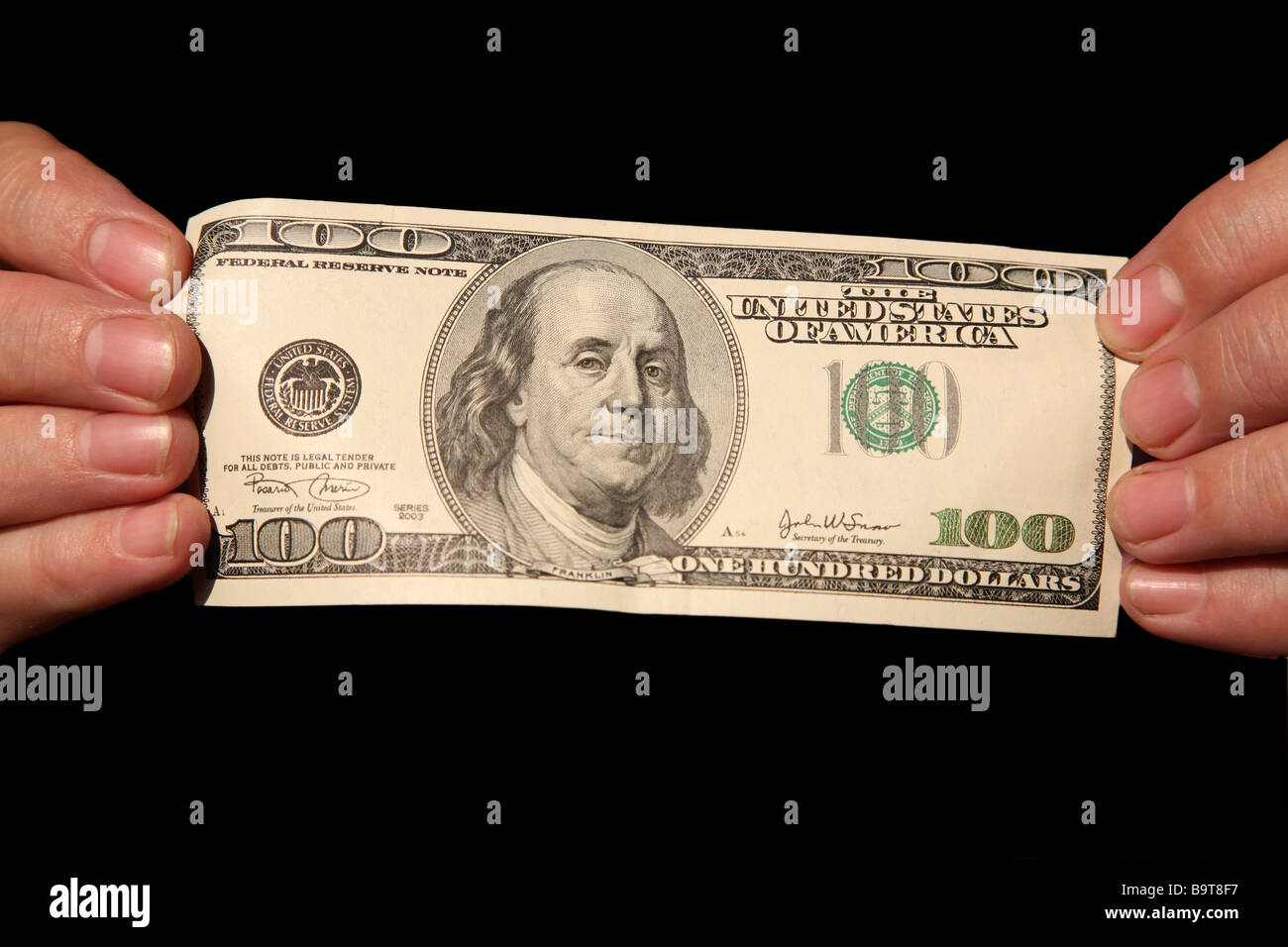 Le mani e un centinaio di dollari su sfondo nero Foto Stock