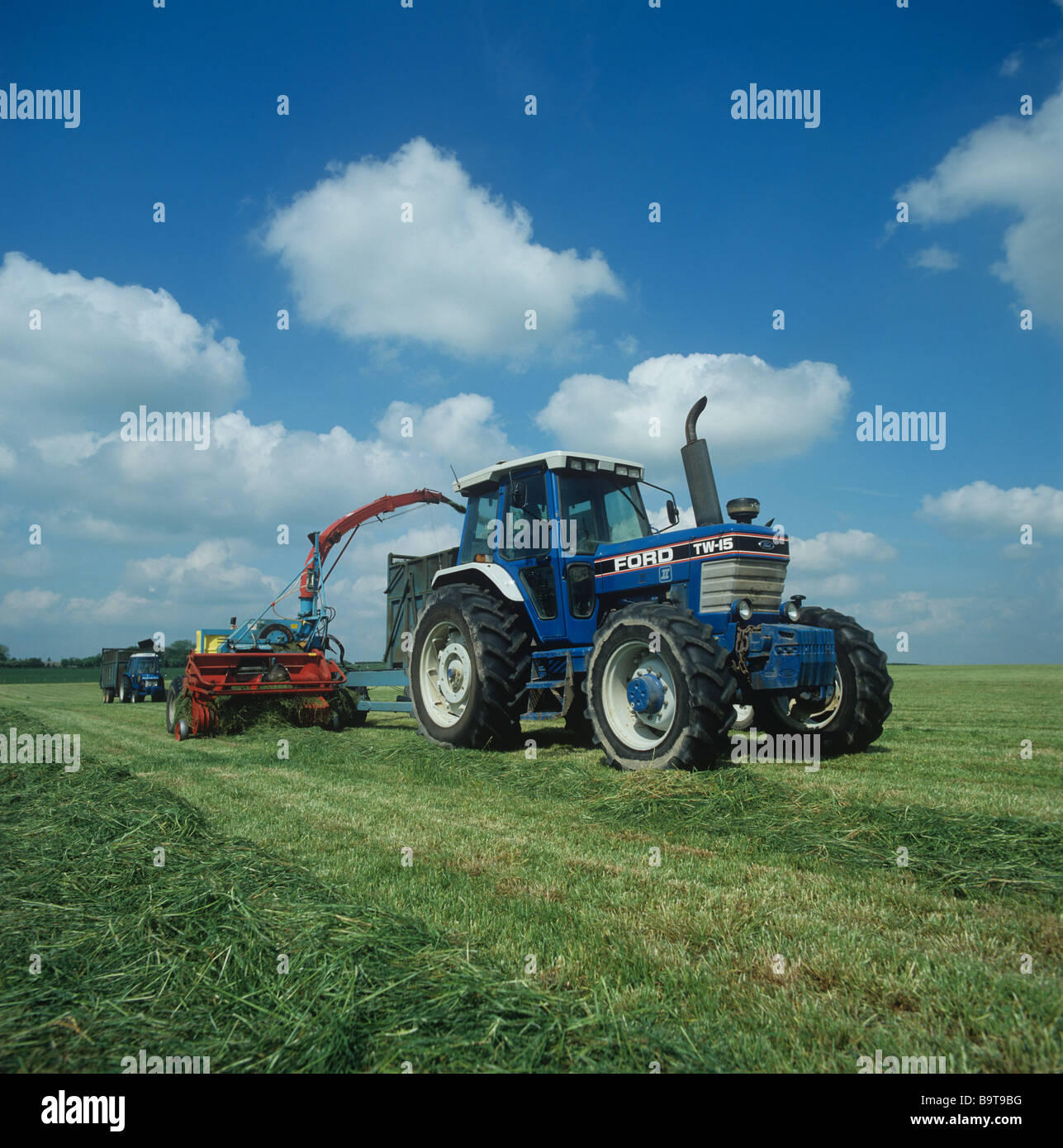 Il trattore rovistando erba tagliata per insilati in una bella giornata sping Hampshire Foto Stock