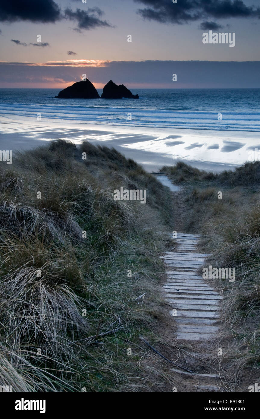 Sole che tramonta dietro Gull Rock sulla spiaggia di Holywell North Cornwall Foto Stock