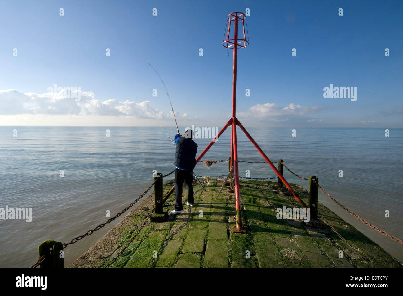 Un uomo la colata di una linea di pesca a partire dalla fine di un pontile sul lungomare di Brighton Regno Unito Foto Stock