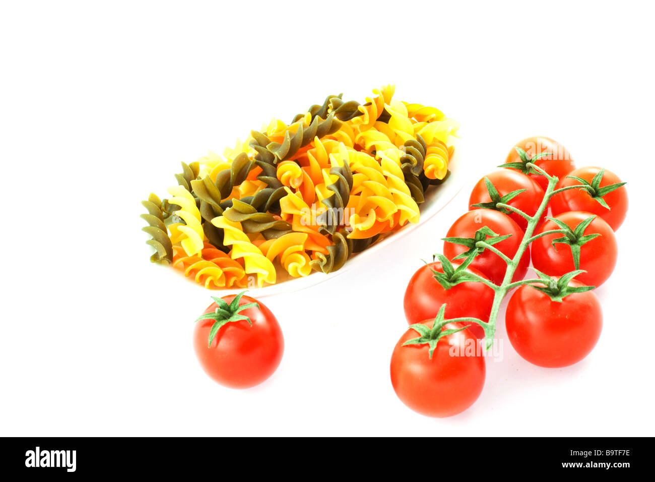 Pasta multicolore un pomodoro e pomodoro grappolo su sfondo bianco Foto Stock