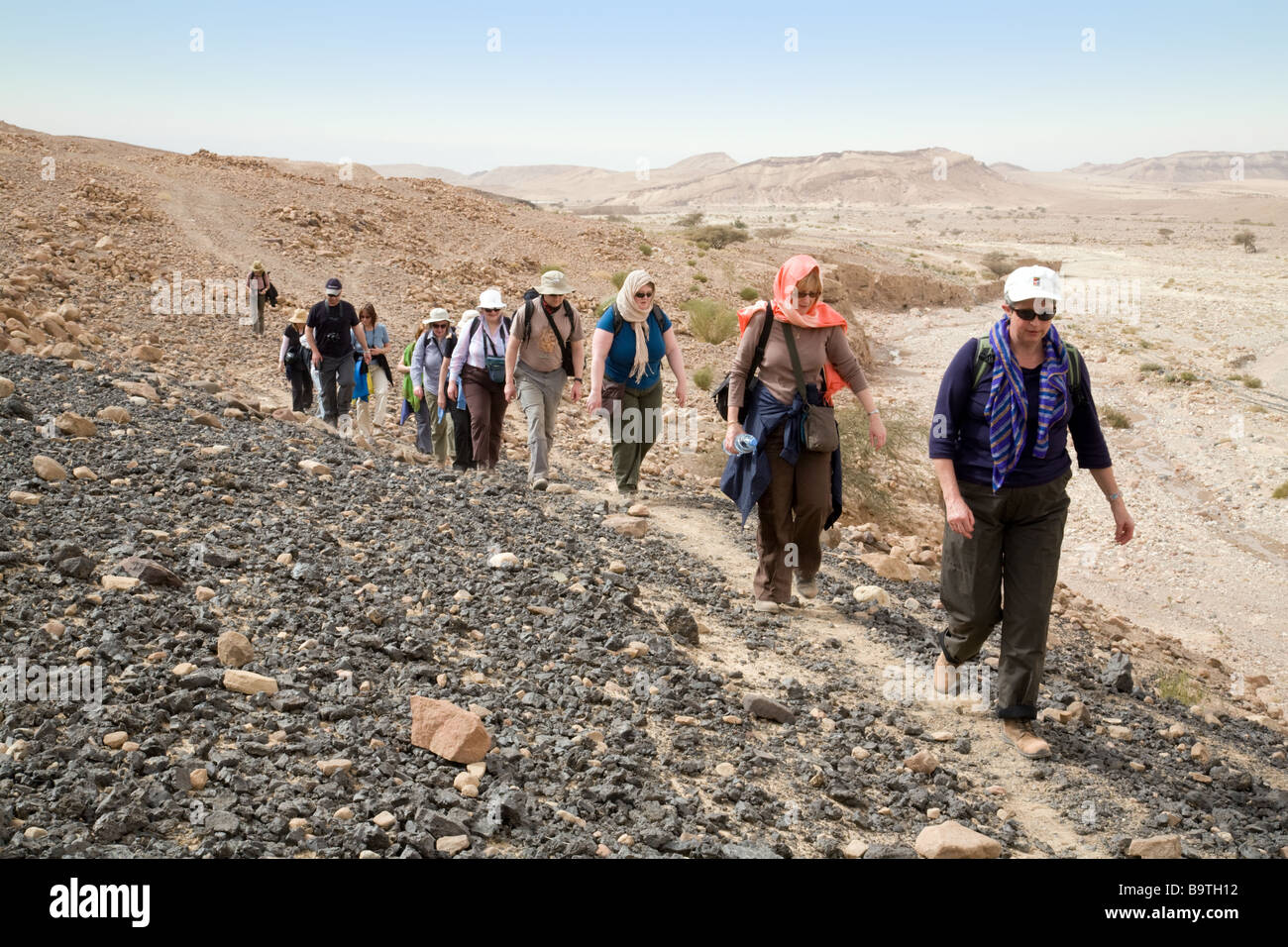 Jordan Tourism; Medio di età compresa tra i turisti a piedi su un tour guidato nel deserto, Dana, Giordania meridionale, Medio Oriente Foto Stock