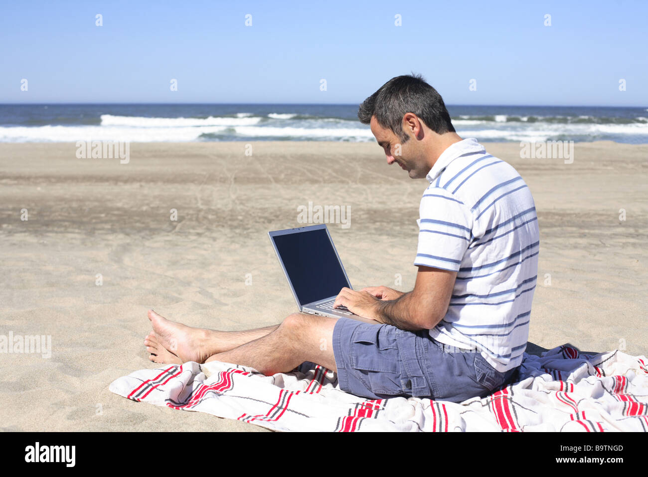 Uomo con notebook sulla spiaggia Foto Stock