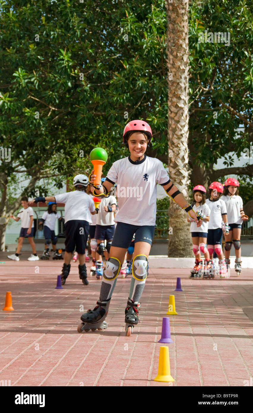 Squadre di junior scuola gli alunni competere in slalom rollerblade corso con la palla e la tazza di concorrenza di bilanciamento Foto Stock