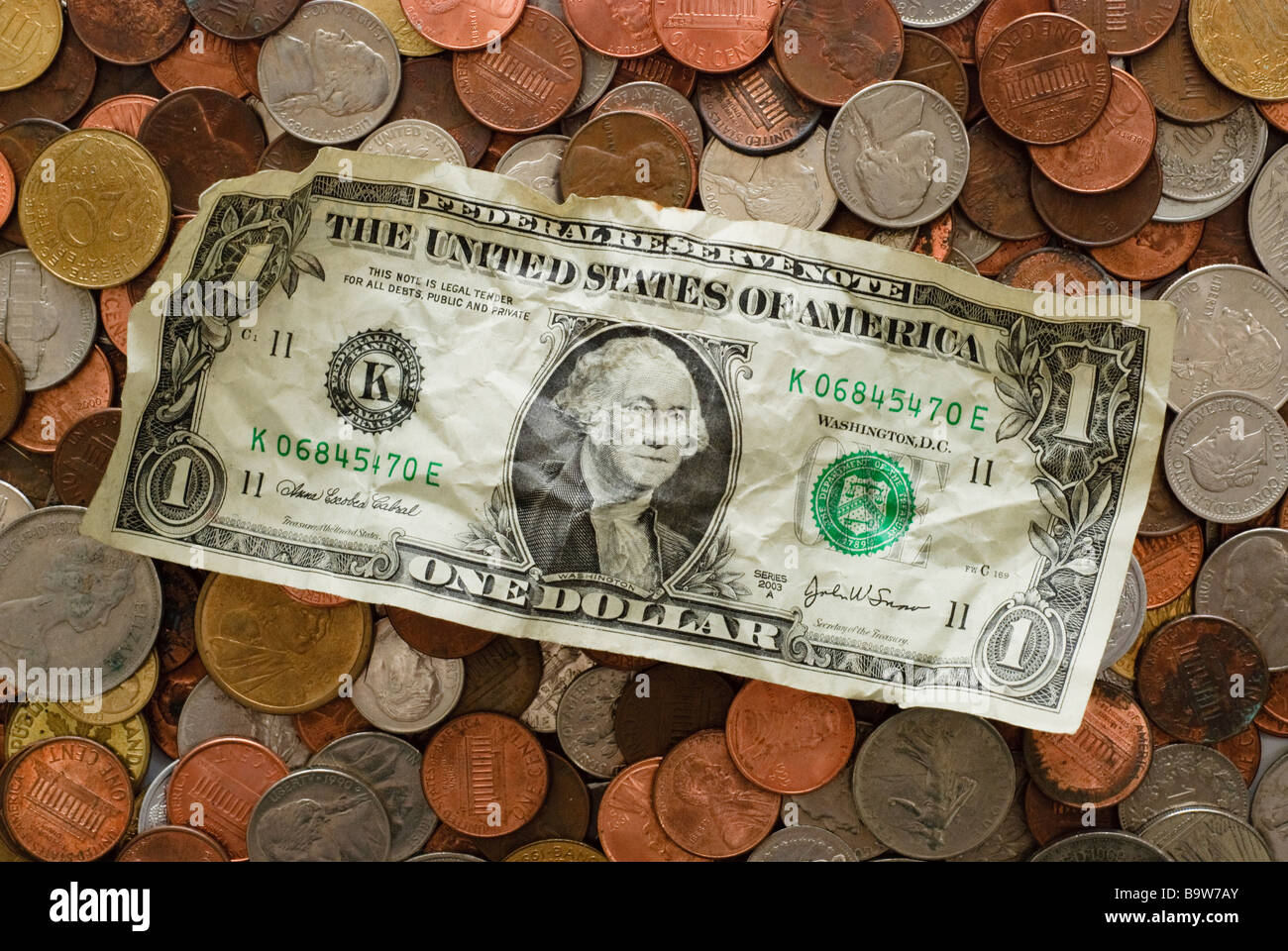 Un accartocciata dollaro al di sopra di uno strato di monete di più valute Foto Stock