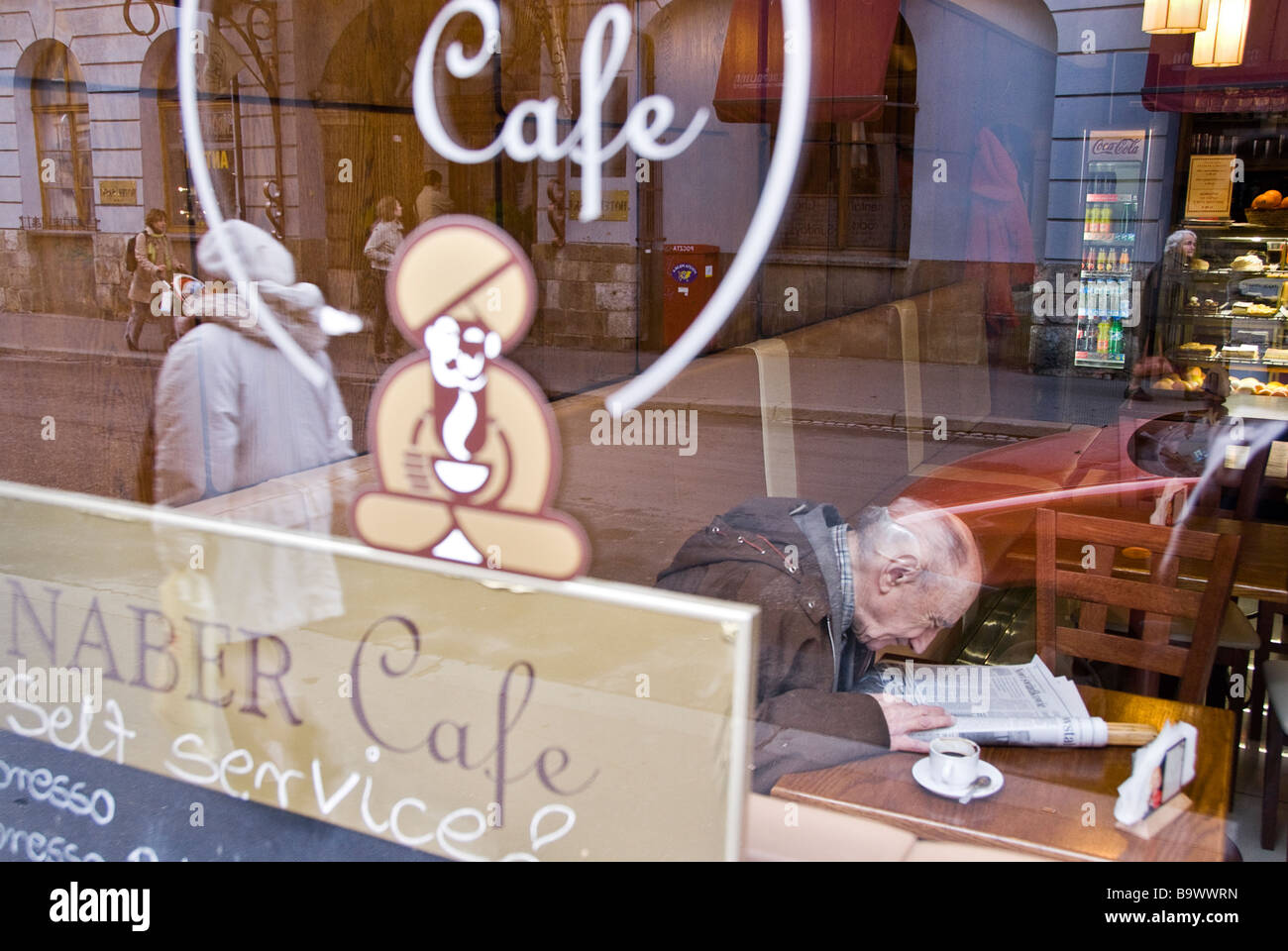 Uomo di bere un caffè e leggere il giornale in un bar. Cracovia, in Polonia, in Europa. Foto Stock