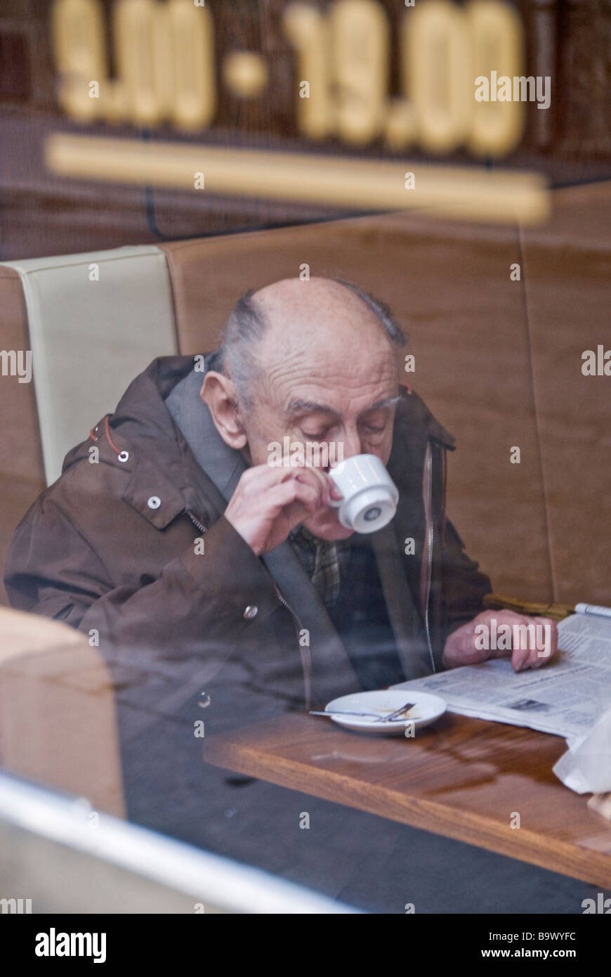 Uomo di bere un caffè e leggere il giornale in un bar. Cracovia, in Polonia, in Europa. Foto Stock