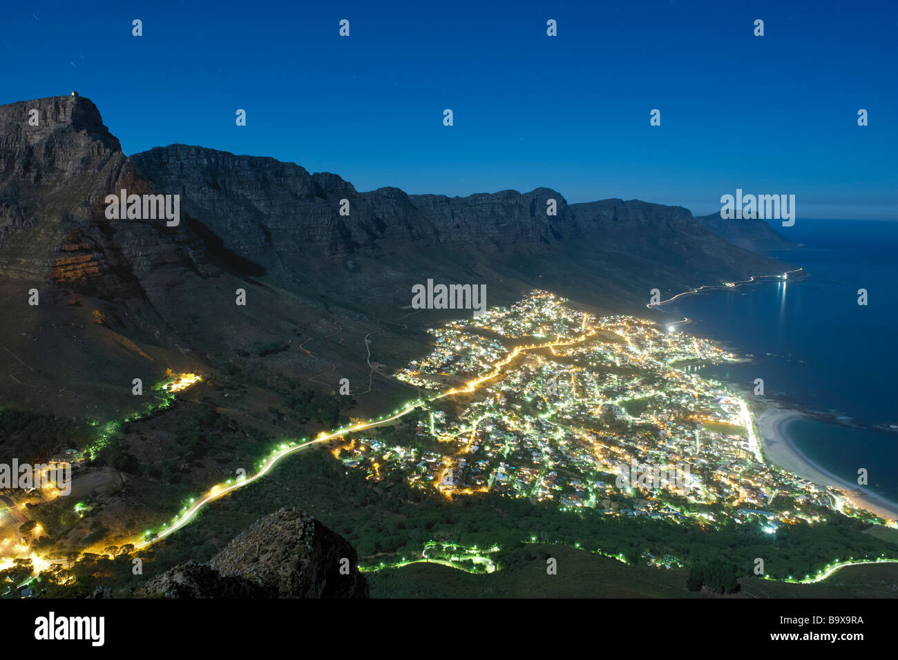 Notte di Luna, vista del sobborgo di Camps Bay e i dodici Apostoli montagne di Città del Capo in Sud Africa. Foto Stock