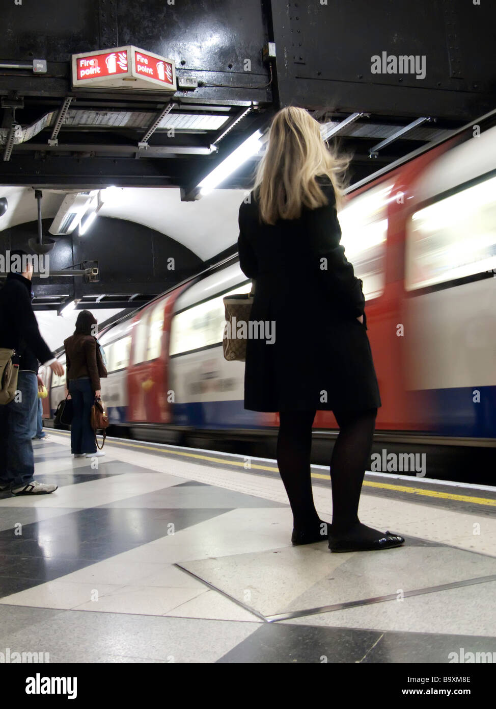 Un film come immagine di una giovane donna in attesa di ottenere su una metropolitana come esso precipita nella stazione. Foto Stock