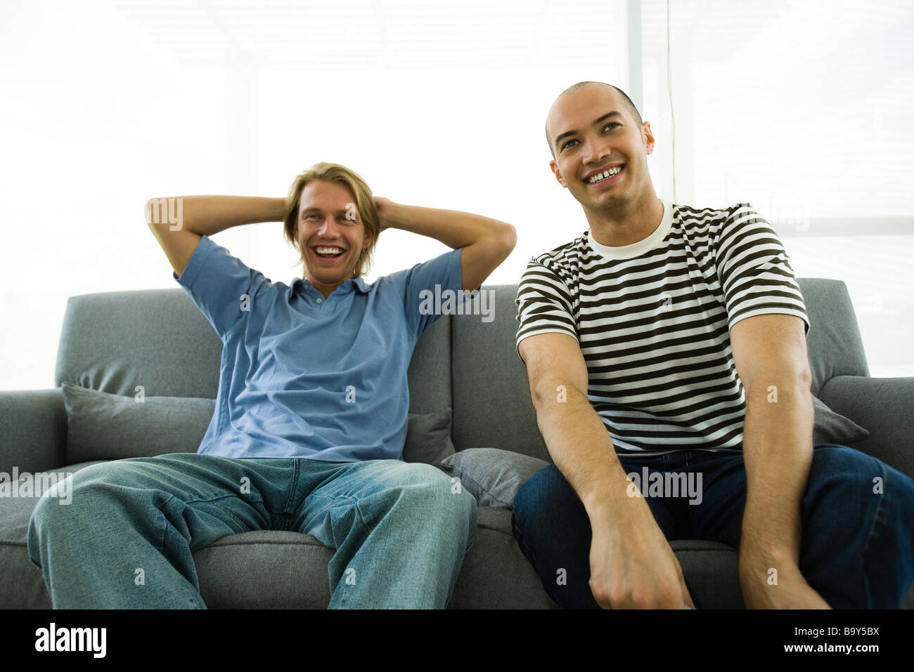 Due uomini seduti sul divano, ridendo Foto stock - Alamy