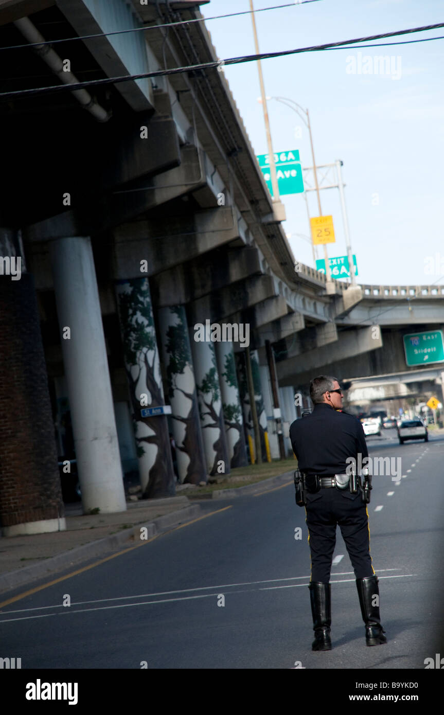 New Orleans funzionario di polizia in attesa vicino alla I-16 vicino a rampa Claiborne Avenue per indirizzare il traffico per un attraversamento del Mardi Gras galleggiante Foto Stock