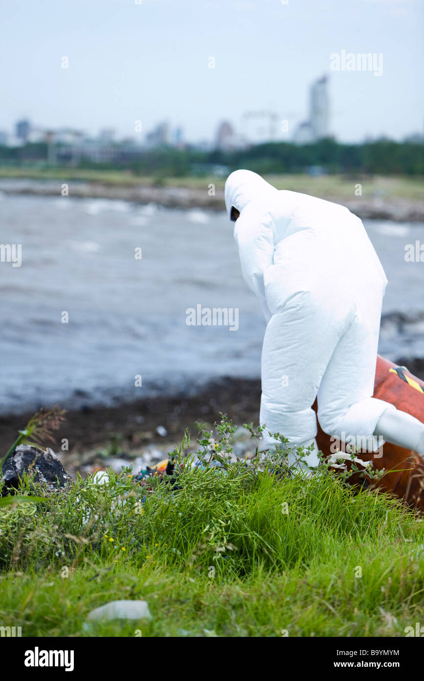 Persona in tuta protettiva per ripulire il litorale inquinato Foto Stock
