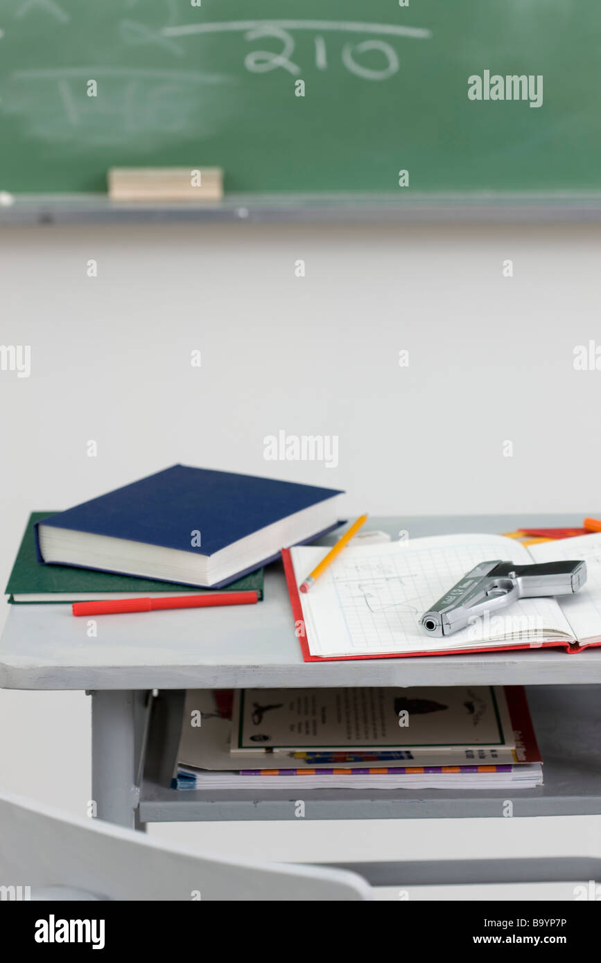 Pistola giacente sulla parte superiore del banco di scuola Foto Stock
