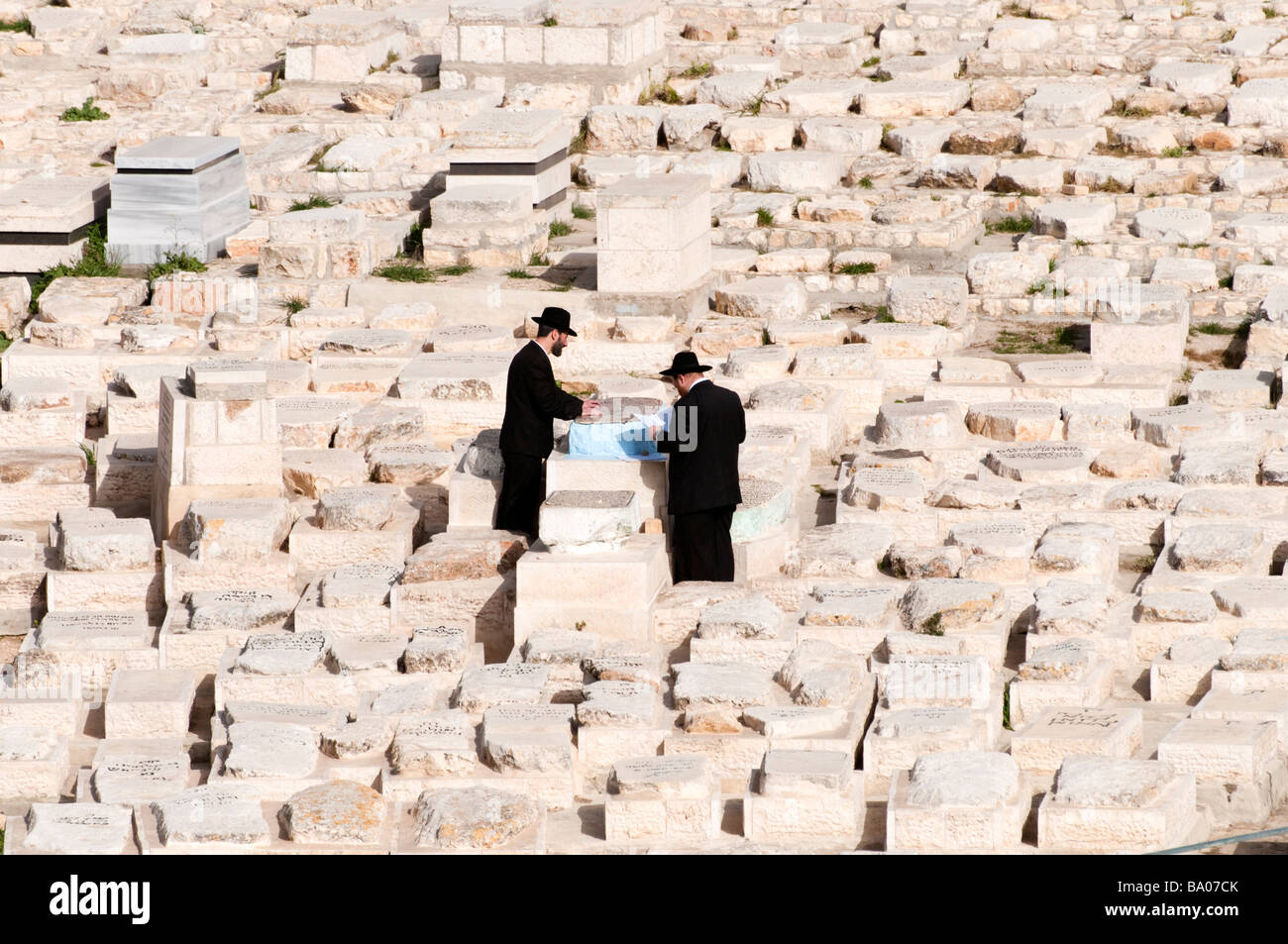 Gli ebrei ortodossi facendo leva in corrispondenza di una delle tombe nel cimitero sul Monte degli Ulivi a Gerusalemme, Israele Foto Stock