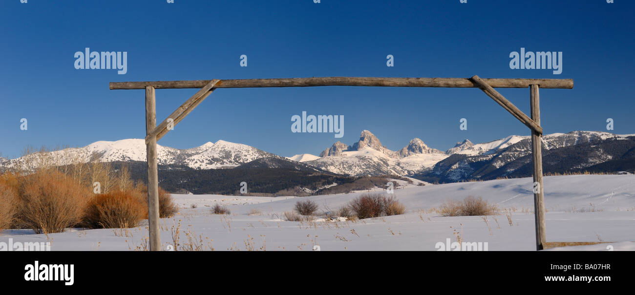 Panorama del monte Owen Grand Centro e Sud Teton picchi Wyoming usa in inverno da un campo di Idaho con legno post gate e cielo blu Foto Stock