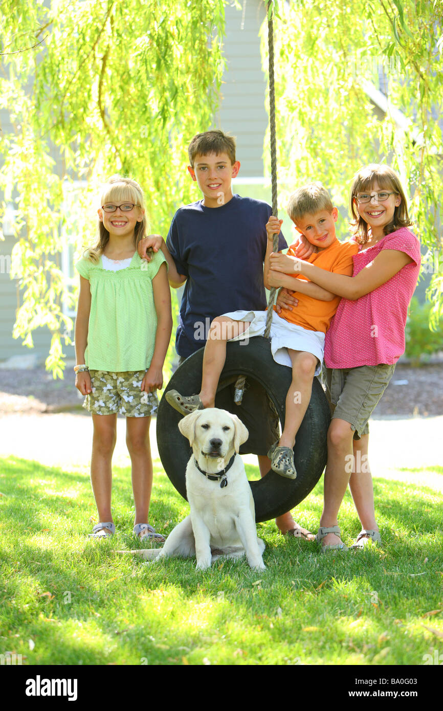 Un gruppo di bambini con tire swing e cane Foto Stock