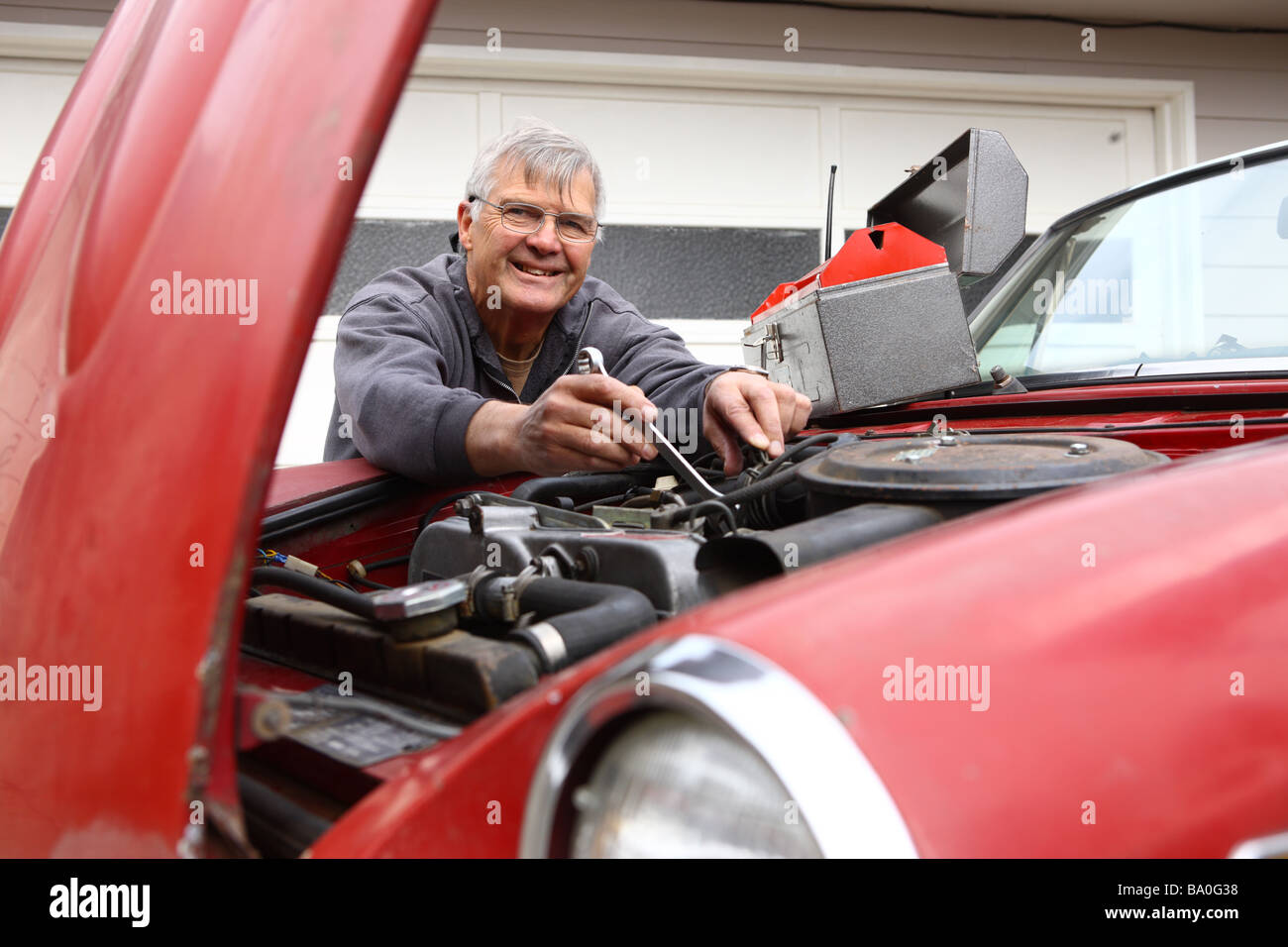 Senior uomo al lavoro su un auto classica Foto Stock