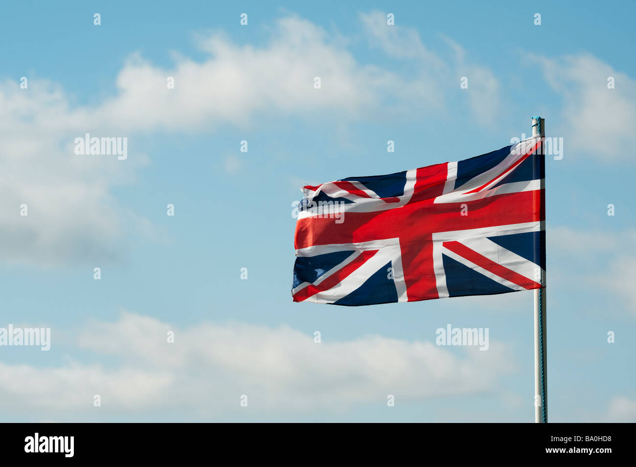 Union Jack flag sbattimenti nel vento contro un blu cielo nuvoloso. Regno Unito Foto Stock