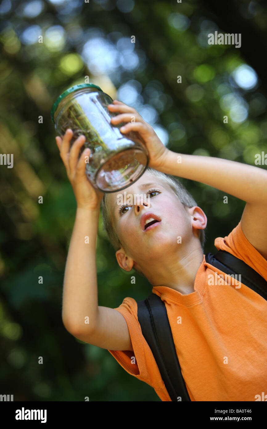 Ragazzo giovane trattiene un vaso con gli insetti Foto Stock