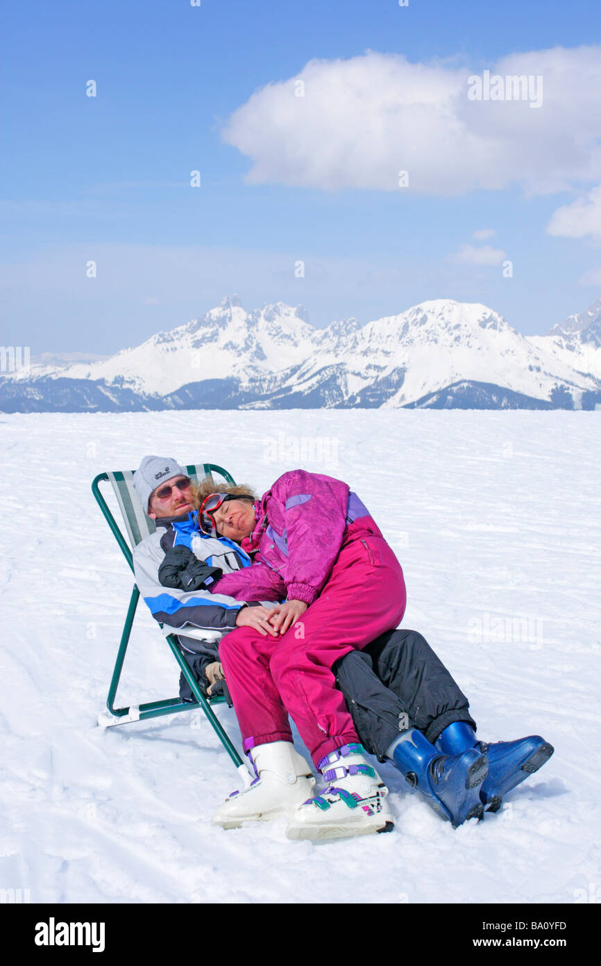 Coppia giovane in appoggio in una sedia di tela a Reiteralm in Stiria, in background Dachstein Mountain, Austria Foto Stock